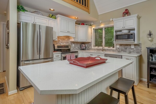 A modern kitchen with white cabinetry, stainless steel appliances, and a large island.
