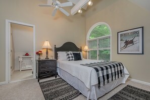A bedroom with a bed, two bedside lamps, a ceiling fan, a window with blinds, a framed picture on the wall, and a white dresser. - Georgia's Place by Taylor Made Deep Creek (Swanton)