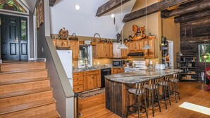 Eine geräumige Küche mit Holzausbau, einer großen Kochinsel mit Barhocker und einer rustikalen Decke.