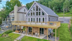 A large house with a balcony, outdoor seating, and a stone patio. - Glencoe by Taylor Made Deep Creek (Oakland)