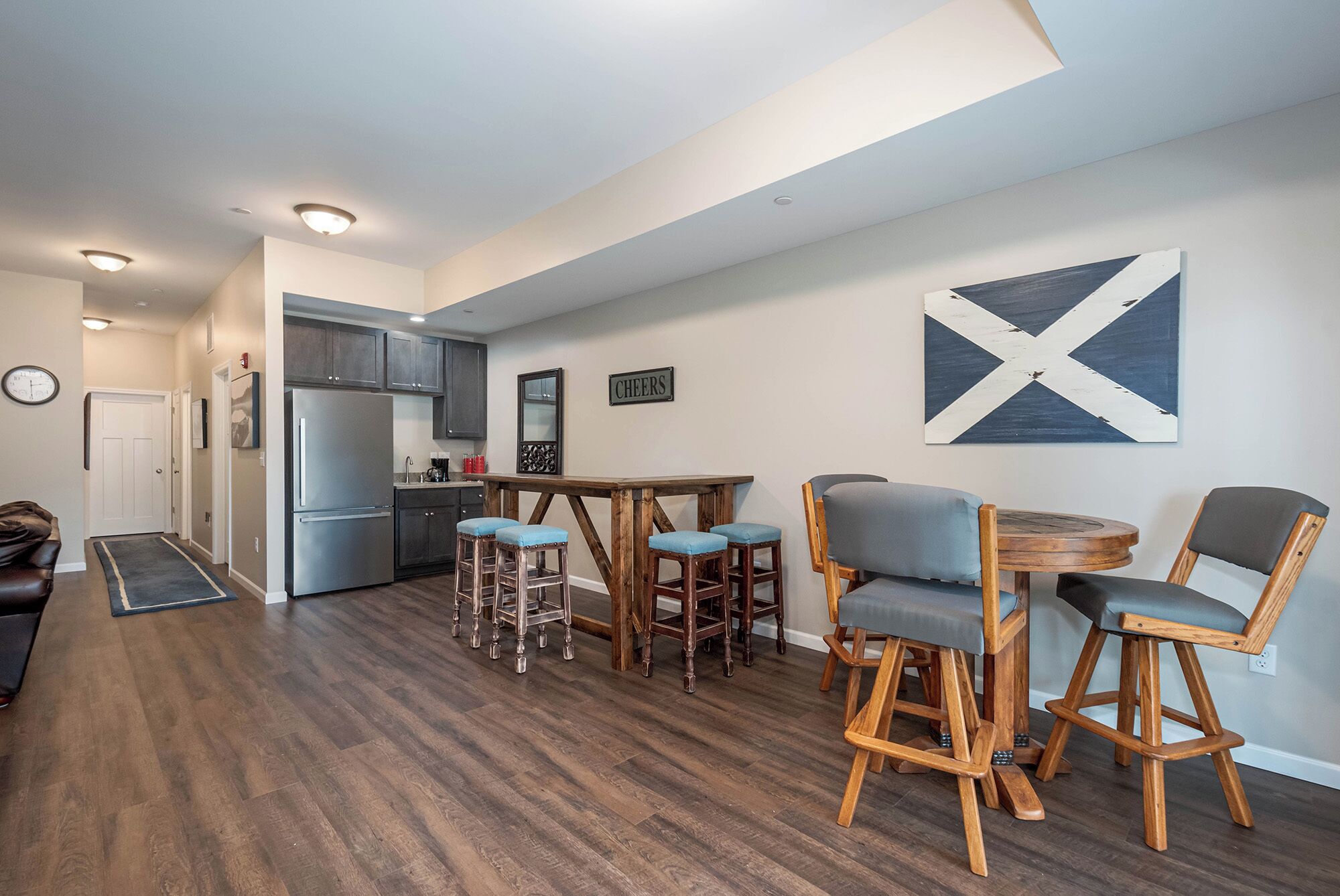Una cocina moderna con armarios de madera oscura, un refrigerador de acero inoxidable y una zona de bar con taburetes.