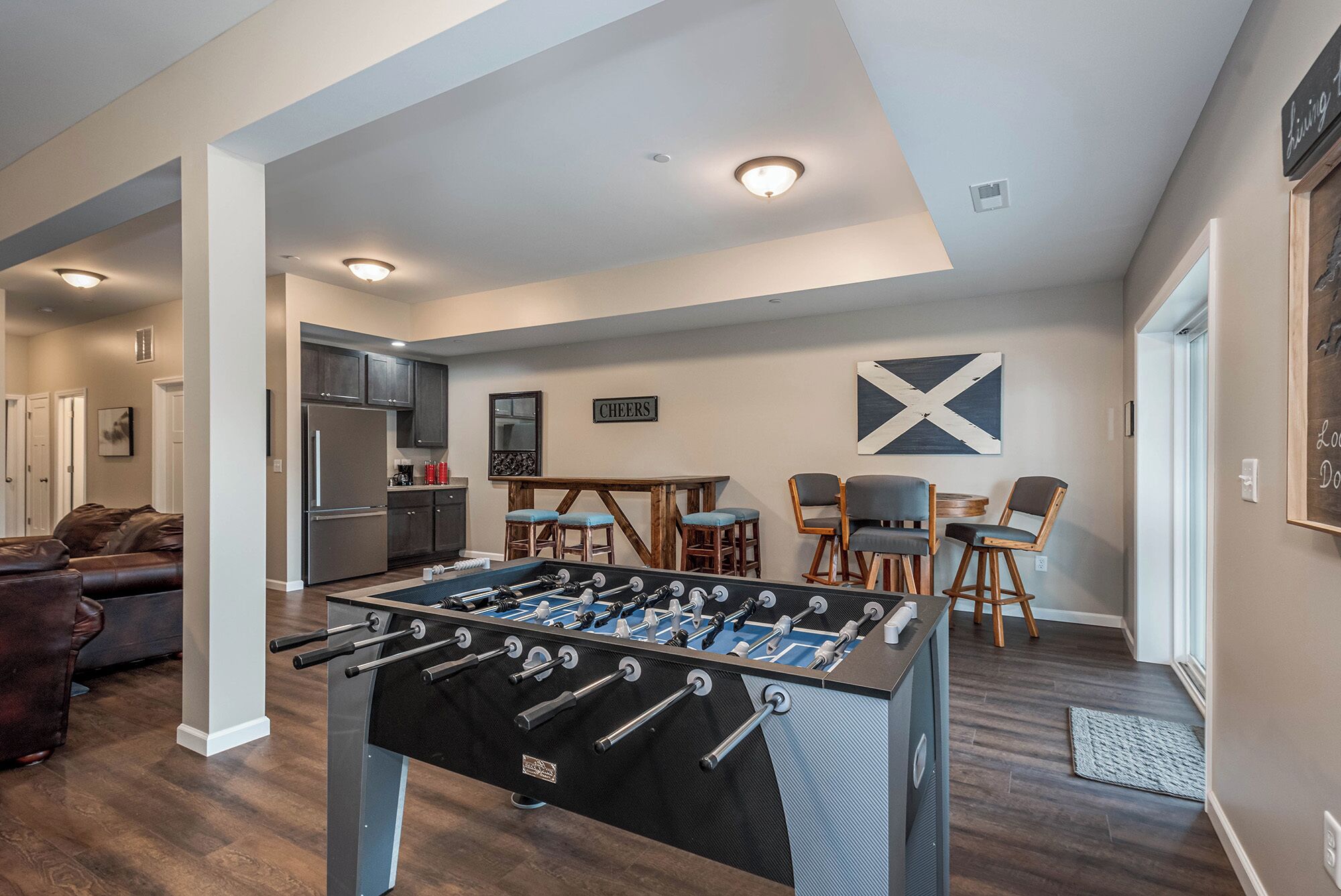 A modern living room with a foosball table, a kitchen, and a dining area.