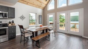 A spacious kitchen with modern appliances, a wooden ceiling, and large windows offering a view of the outdoors. - Glencoe by Taylor Made Deep Creek (Oakland)