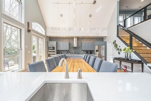 A modern kitchen with a central island, stainless steel appliances, and a large window overlooking a balcony.