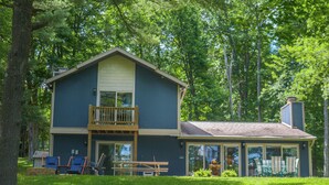 A two-story house with a balcony, a covered patio, and a fire hydrant in the yard. - Golden Pond by Taylor Made Deep Creek (Swanton)