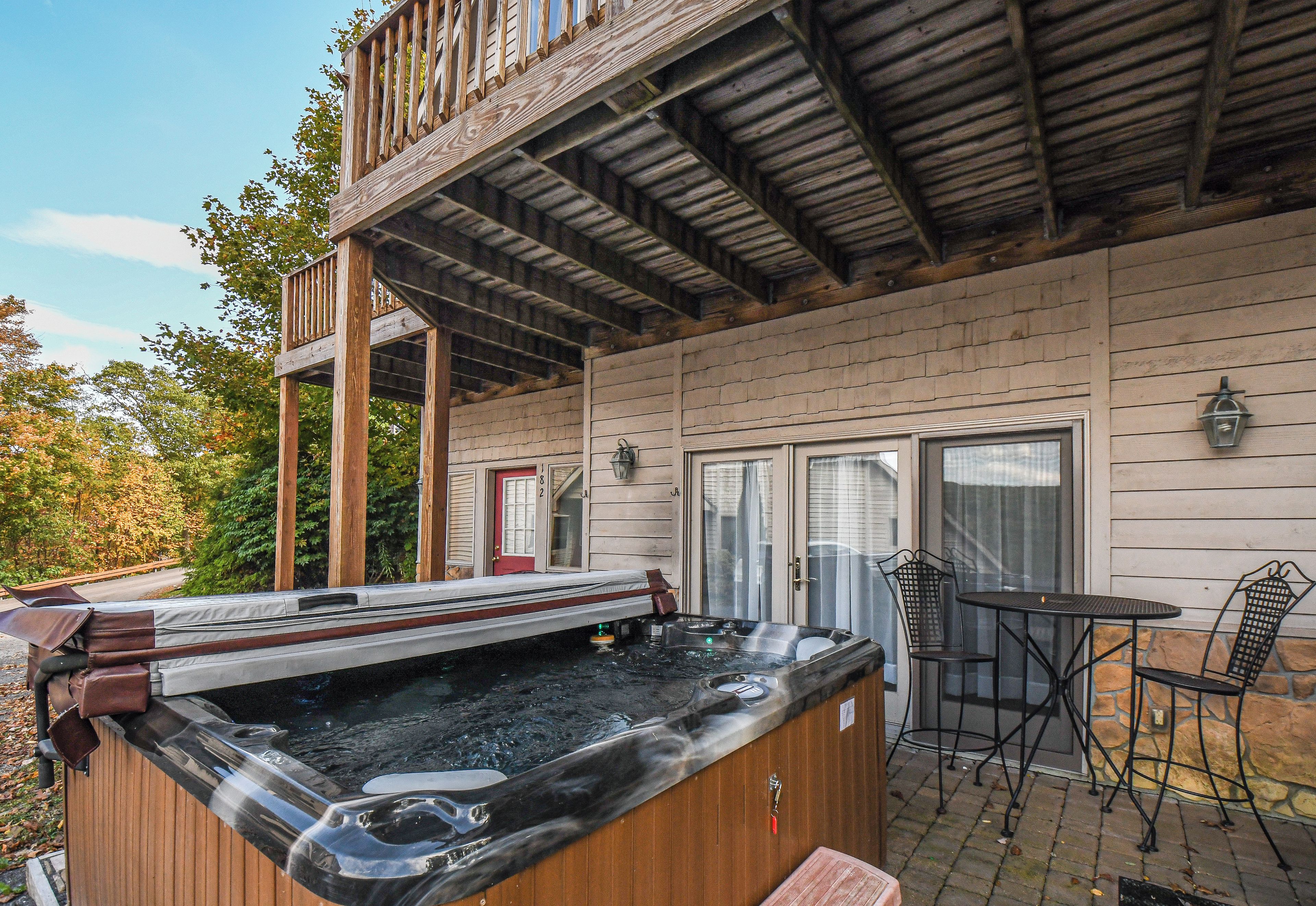 Ein Whirlpool mit einer Holzterrasse und einem Tisch mit Stühlen.