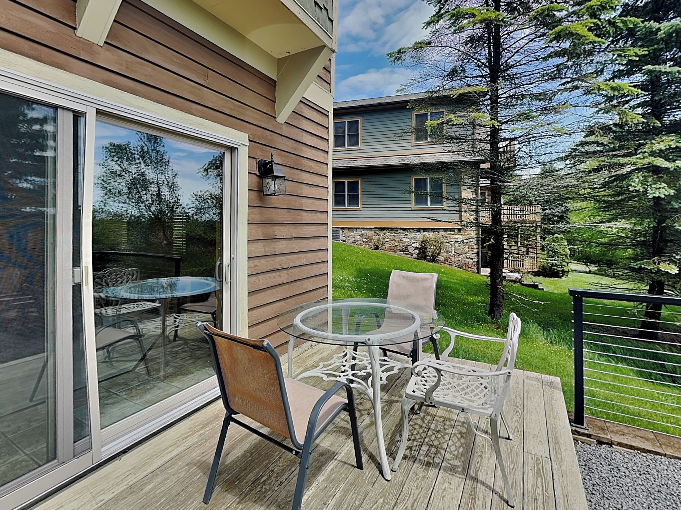 A deck with a glass door leading to a patio, a round table, and two chairs.