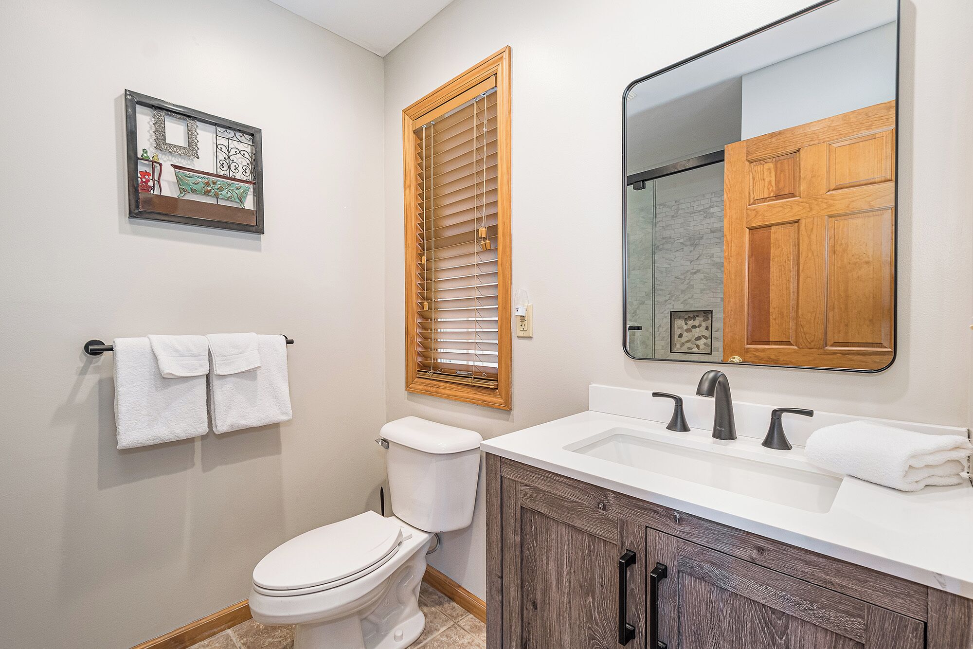A bathroom with a toilet, sink, and mirror.