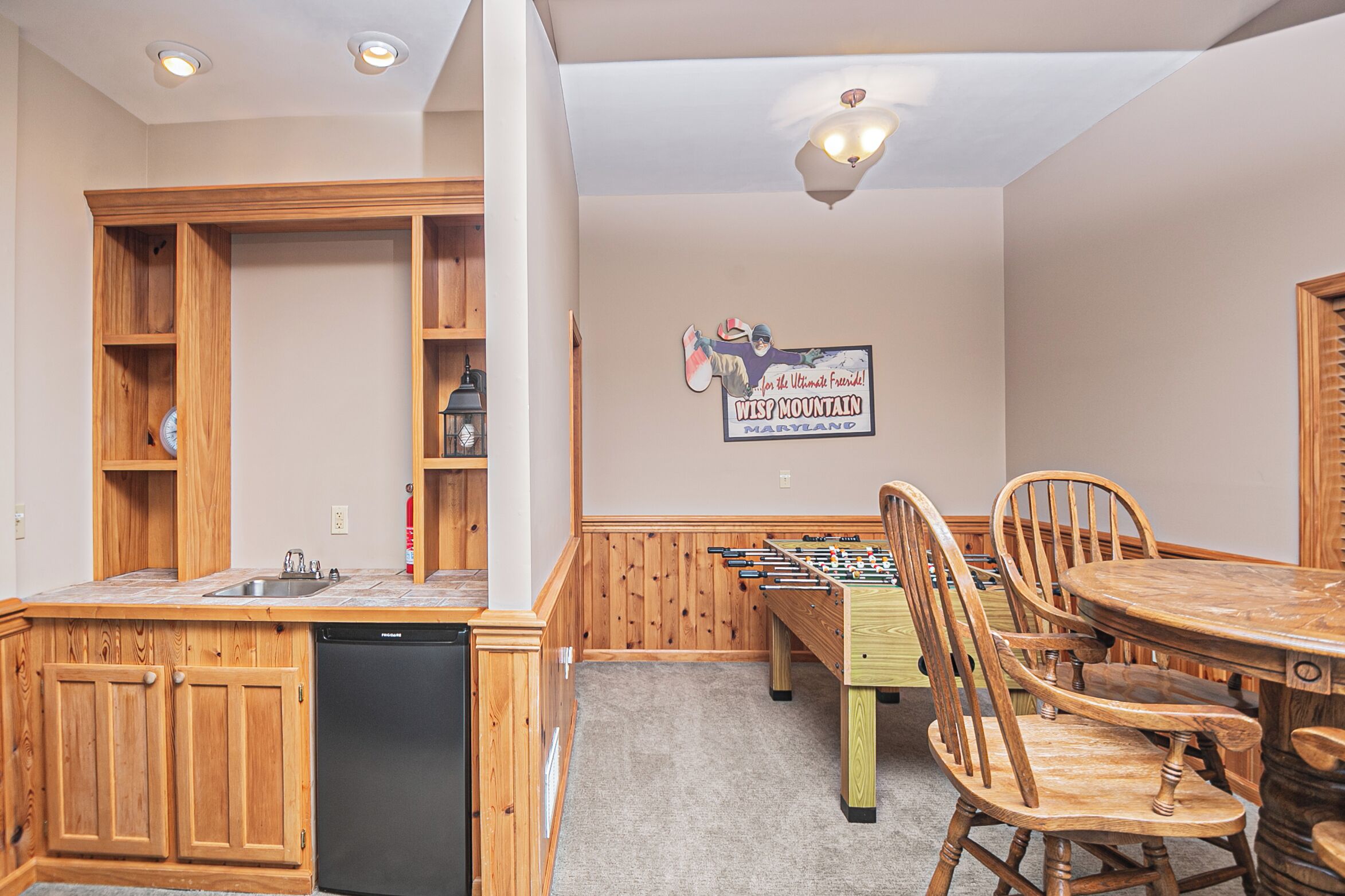 A room with wooden cabinets, a foosball table, and a dining table with chairs.