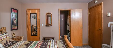 Un dormitorio con cama, cabecera de madera, espejo, puerta y ventilador.