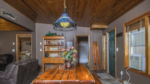 Une table à manger en bois, agrémentée d’un vase de fleurs, une bibliothèque et un plafond en bois.
