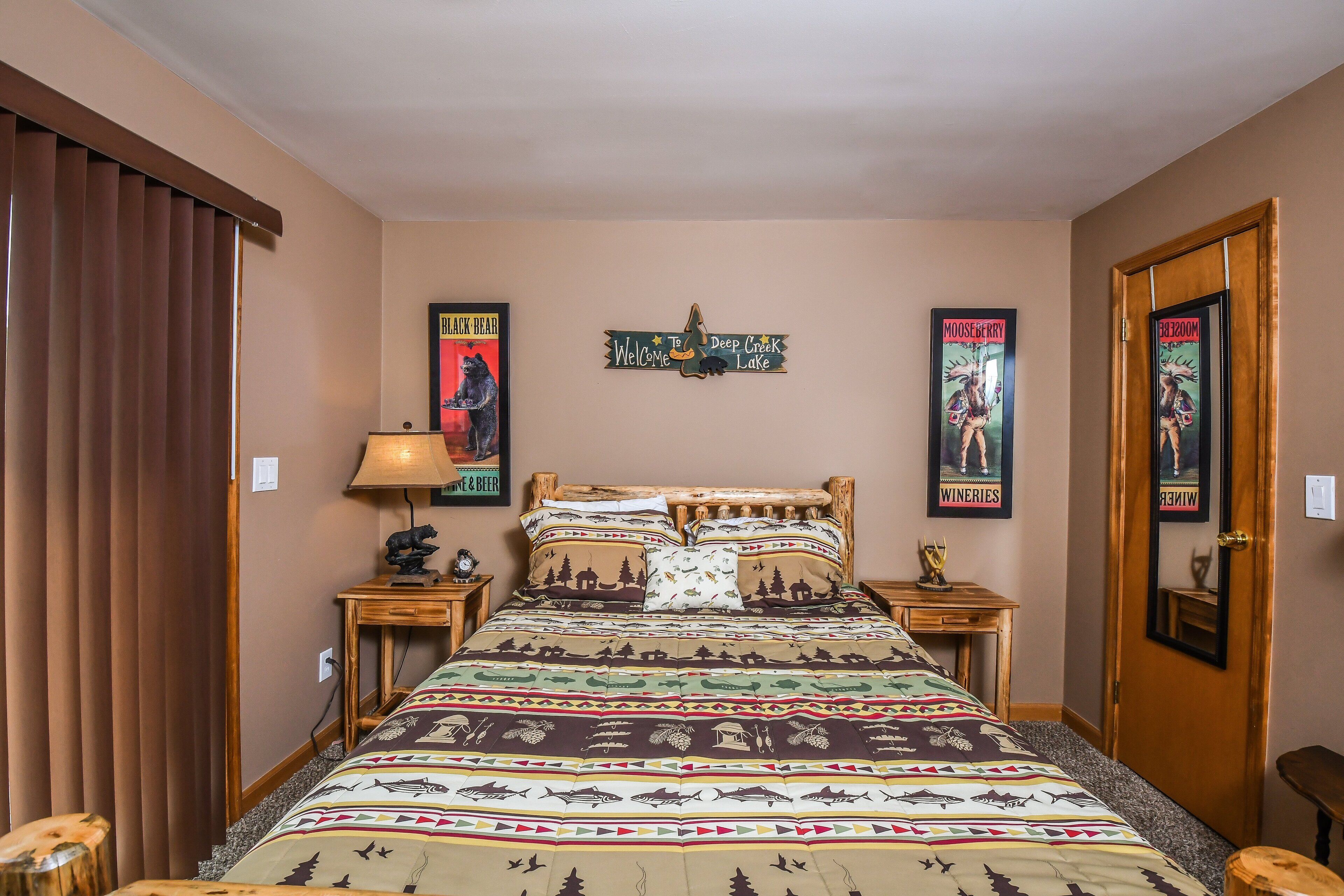 A bedroom with a bed, wooden headboard, two nightstands, a lamp, and wall decorations including posters and a sign.