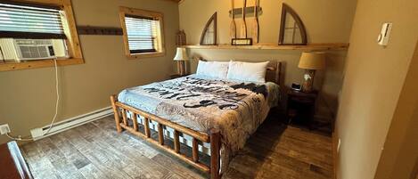 A bedroom with a wooden bed frame, a ceiling fan, two bedside lamps, and a window with blinds.