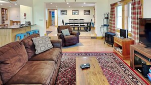 A cozy living room with a brown leather sofa, a wooden coffee table, and a television. - Happy Trails by Taylor Made Deep Creek (Oakland)