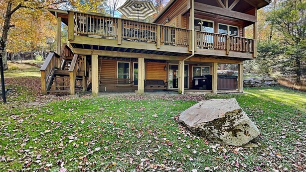A two-story log cabin with a balcony, a porch, and a large rock in front. - Happy Trails by Taylor Made Deep Creek (Oakland)