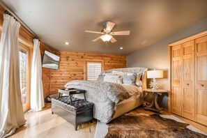 A bedroom with a bed, a ceiling fan, a wooden wardrobe, and a window with curtains. - Happyplace Hideaway by Taylor Made Deep Creek (McHenry)