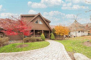 A log cabin with a curved driveway, surrounded by autumn foliage and a well-maintained lawn. - Happyplace Hideaway by Taylor Made Deep Creek (McHenry)