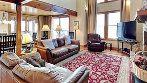A spacious living room with a large leather sofa, a red patterned rug, and a television. - Hawk Mountain by Taylor Made Deep Creek (McHenry)