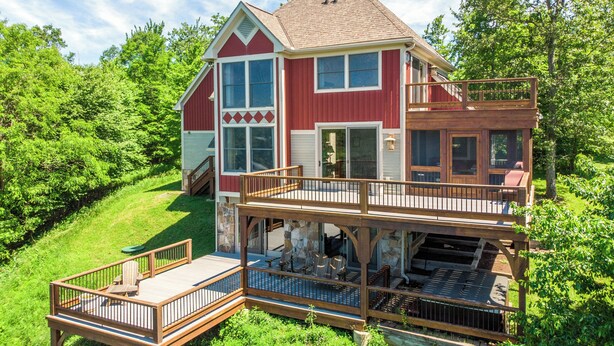 A two-story house with a deck, large windows, and a stone foundation. - Hawk Mountain by Taylor Made Deep Creek (McHenry)