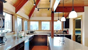 A modern kitchen with wooden beams, large windows, and a central island. - Hawk Mountain by Taylor Made Deep Creek (McHenry)