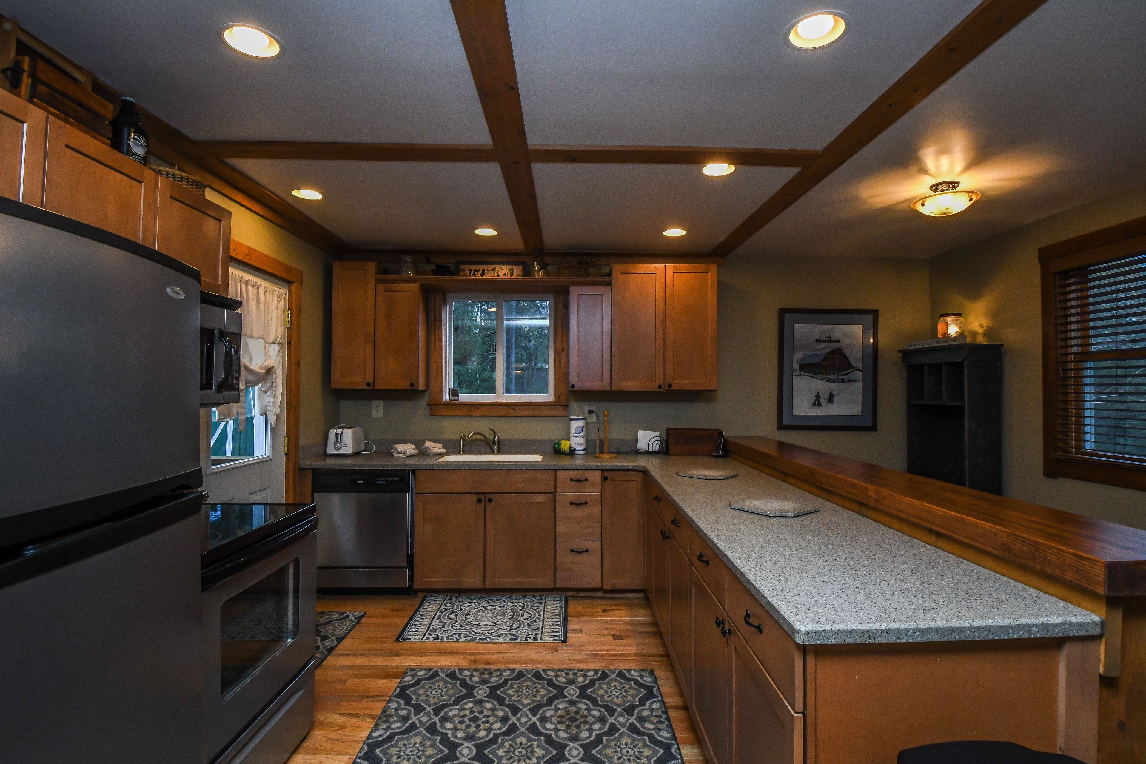 A modern kitchen with wooden cabinets, a stainless steel refrigerator, and a granite countertop.