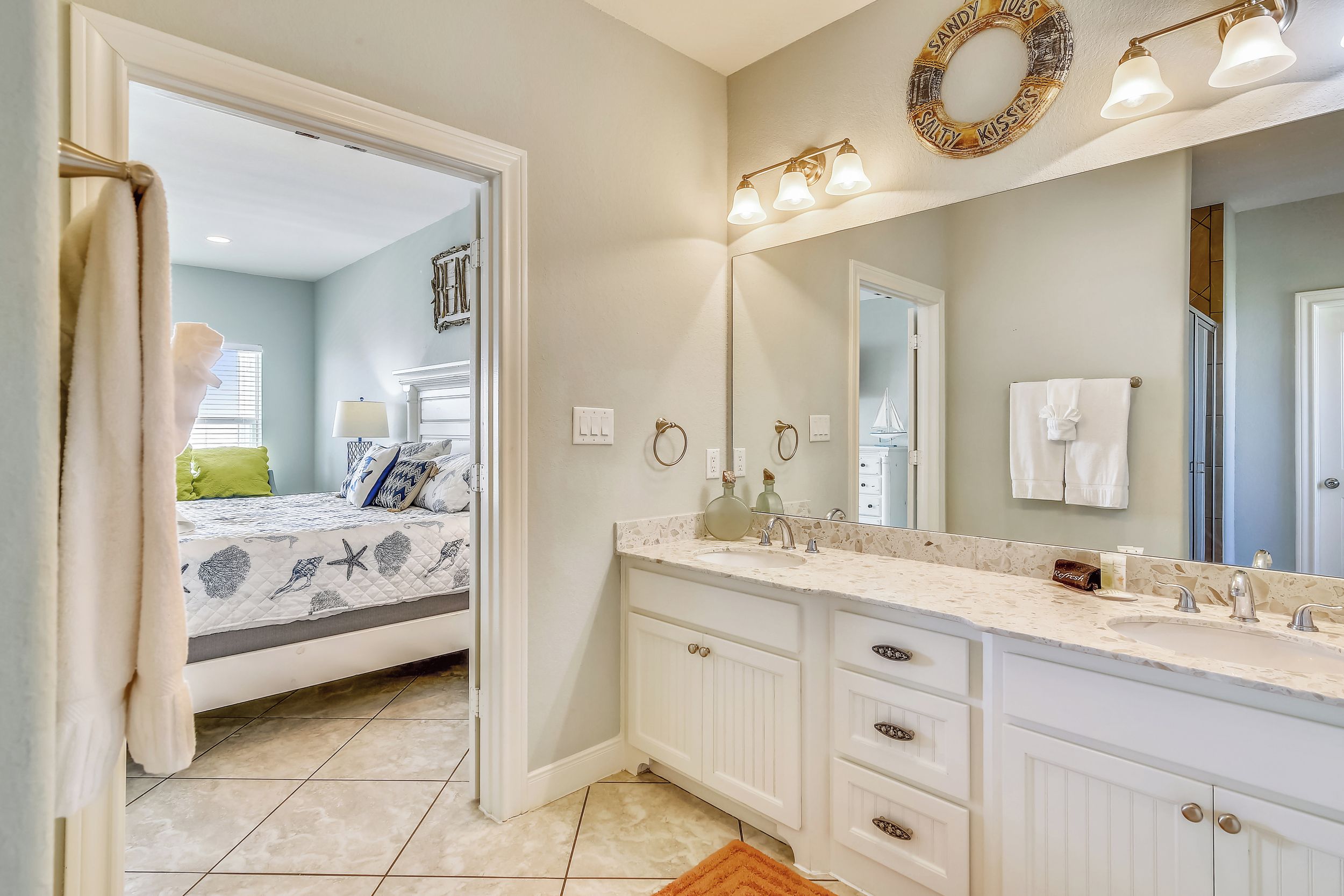A bathroom with a large mirror, a sink, and a vanity with drawers.