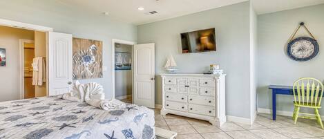 A bedroom with a bed, a dresser, a chair, a ceiling fan, and a wall clock.