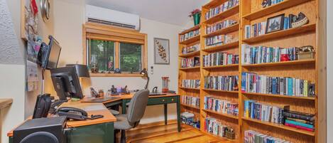 A study room with a desk, chair, bookshelf, and a window.