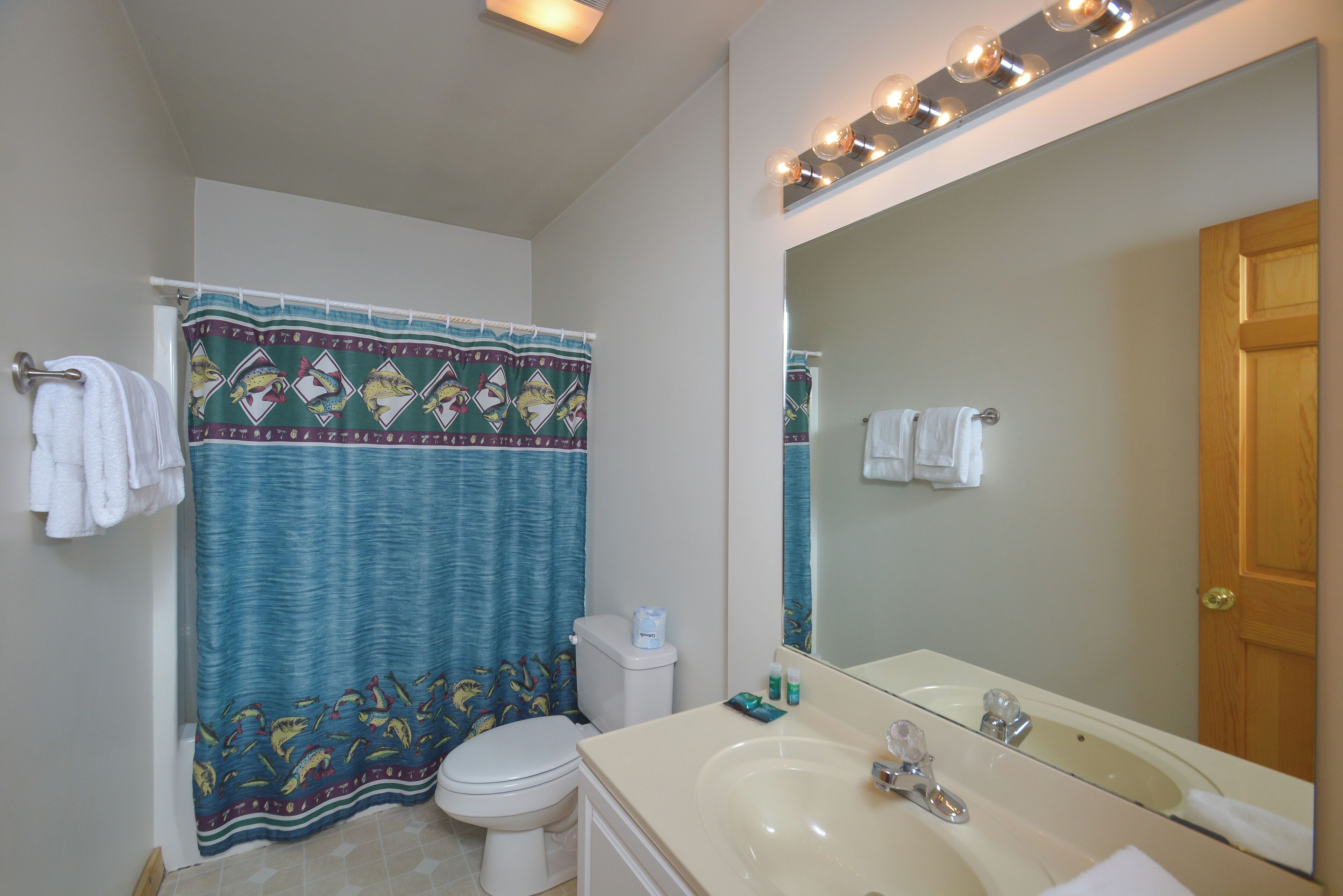 Une salle de bain avec des toilettes, un lavabo et un rideau de douche.