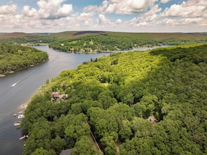 Eine Luftaufnahme eines Sees, der von dichtem Wald und Hügeln umgeben ist.