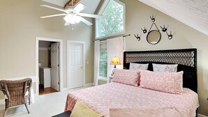 Ein Schlafzimmer mit Bett, Stuhl, Deckenventilator, Fenster und Tür.