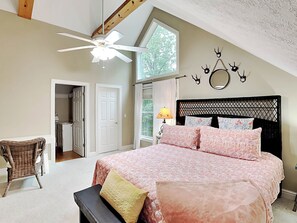 A bedroom with a bed, a chair, a ceiling fan, a window, and a door. - Heavenly Grove by Taylor Made Deep Creek (Oakland)