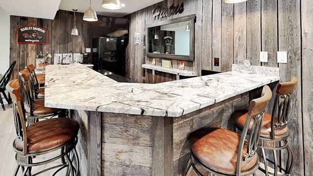 A bar area with a marble countertop, wooden bar stools, and pendant lighting. - Hiatus by Taylor Made Deep Creek (McHenry)