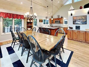 Una cocina amplia con armarios de madera, una isla grande y un comedor con mesa y sillas de madera.