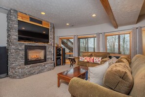 A cozy living room with a stone fireplace, a large flat-screen TV, and a comfortable sofa.