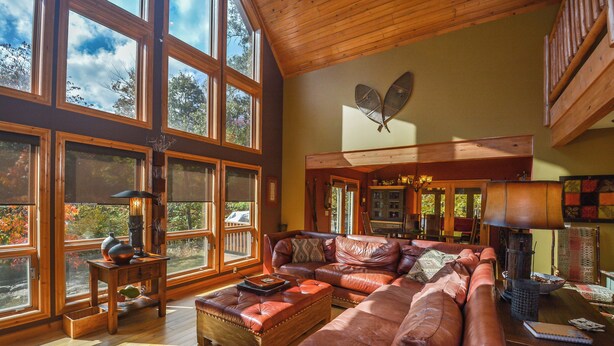 A spacious living room with large windows, a fireplace, and a cozy seating area. - High-skis' Villa by Taylor Made Deep Creek (McHenry)