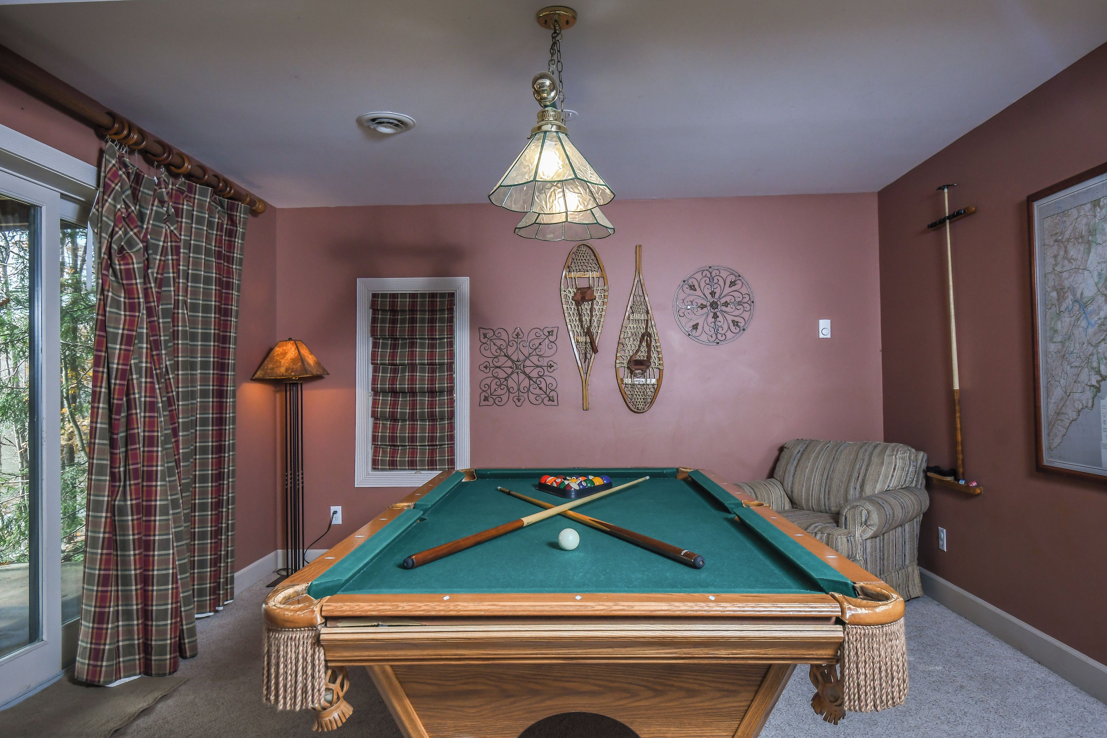 A pool table with a green felt surface, surrounded by a wooden frame.