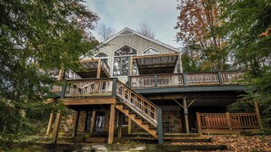 A two-story wooden cabin with a balcony and stairs leading to the upper level. - Highland Retreat by Taylor Made Deep Creek (McHenry)