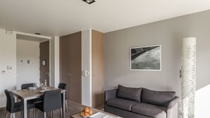 A modern living room with a dining area, grey sofa, and a decorative lamp. - La Guimorais - La Maison du Benetin (Saint-Malo)
