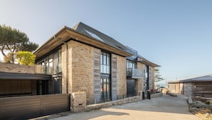A modern building with a stone facade, large windows, and a covered outdoor area. - La Guimorais - La Maison du Benetin (Saint-Malo)
