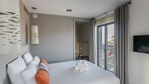 A modern hotel room with a large bed, a flat-screen TV, and a balcony with a view. - La Hoguette - La Maison du Benetin (Saint-Malo)