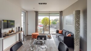 A modern living room with a dining area, a sofa, and a TV. - La Hoguette - La Maison du Benetin (Saint-Malo)
