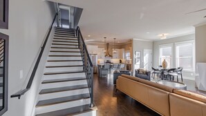 A modern interior with a staircase, a living area with a sofa, and a kitchen.