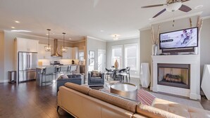 A spacious living area with a large sofa, a fireplace, and a television displaying the Winter Olympics.