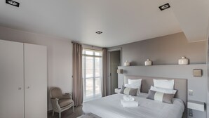 A modern bedroom with a large bed, a wardrobe, a chair, and a bedside table.