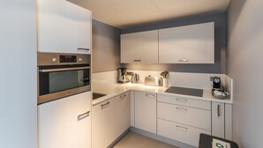A modern kitchen with white cabinets, stainless steel appliances, and a built-in oven.