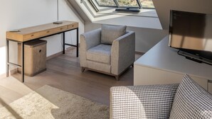 Un dormitorio tipo loft moderno con techo inclinado, tragaluces, un escritorio, un sofá y un televisor.