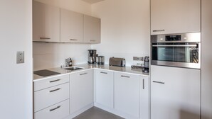 Una cocina moderna con armarios blancos, electrodomésticos de acero inoxidable y un horno empotrado.