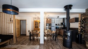 A modern kitchen with a wood stove, dining area with a table and chairs, and a visible kitchen counter.