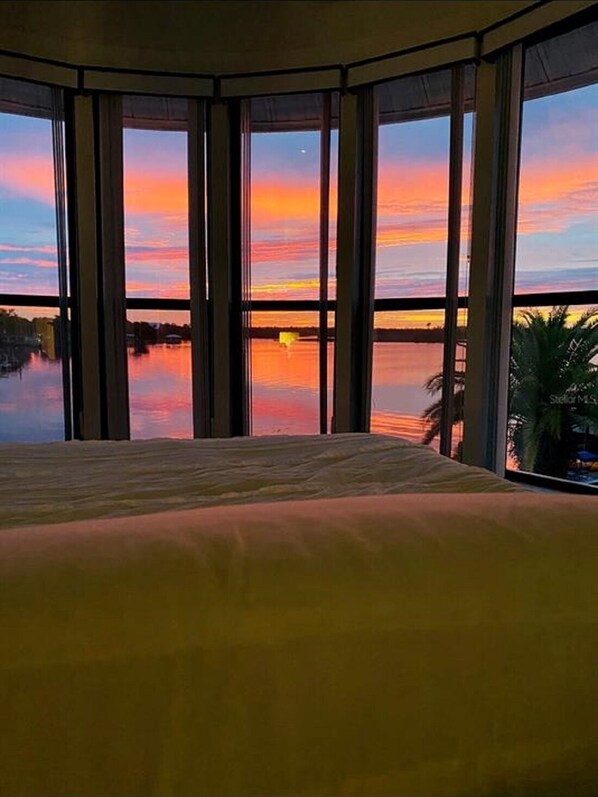 Una stanza con un letto grande e vista su un tramonto sull'acqua.
